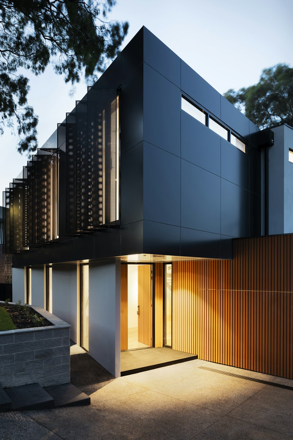 Double-storey rear extension with dark cladding and floor-to-ceiling glazing